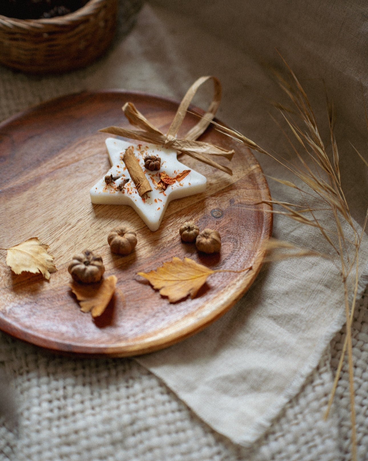 Wooden plate with star-shaped wax melts nuts, and leaves on a textured surface