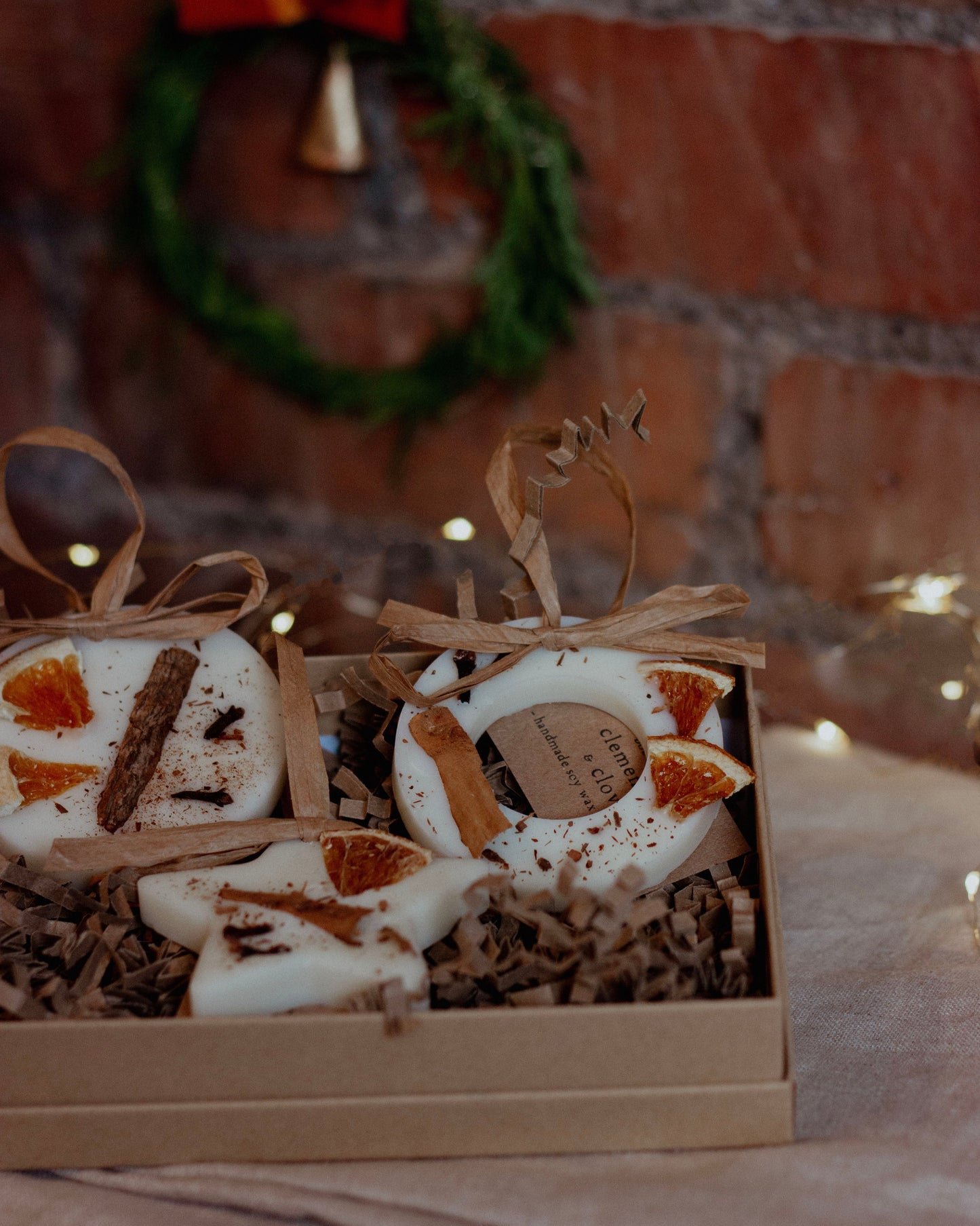 Box of decorative items with a wreath in the background on a brick wall.