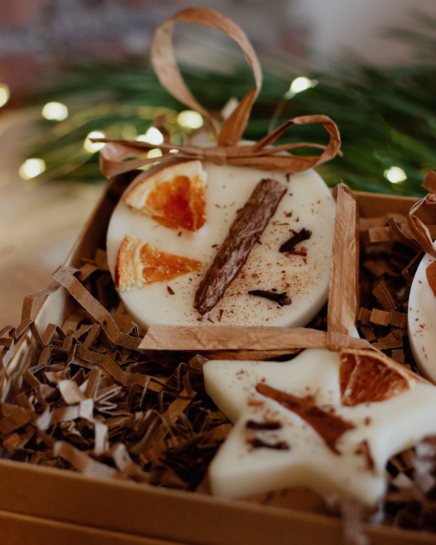 Decorative soap with star and heart shapes, tied with a ribbon, on a bed of straw with a blurred festive background.