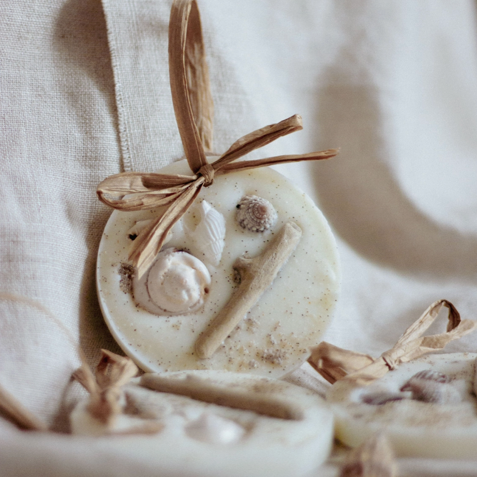 Decorative wax melt with driftwood and shells, complete with raffia bow on a neutral background
