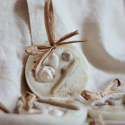 Decorative wax melt with driftwood and shells, complete with raffia bow on a neutral background