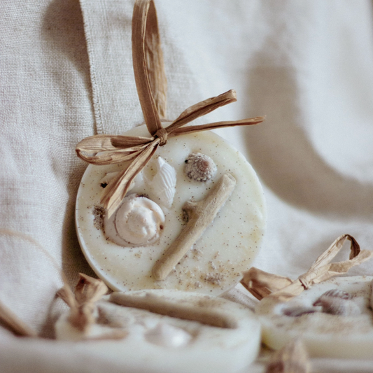 Decorative wax melt with driftwood and shells, complete with raffia bow on a neutral background