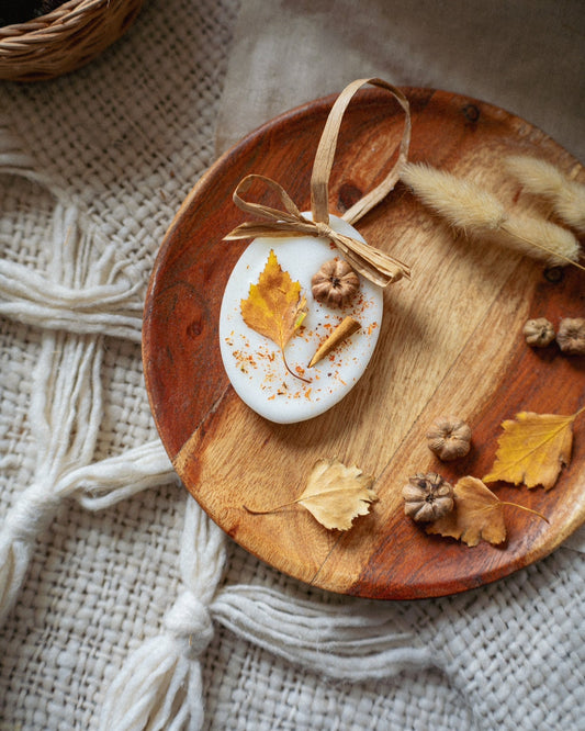 Decorative soap with autumn leaves and a bow on a wooden plate.