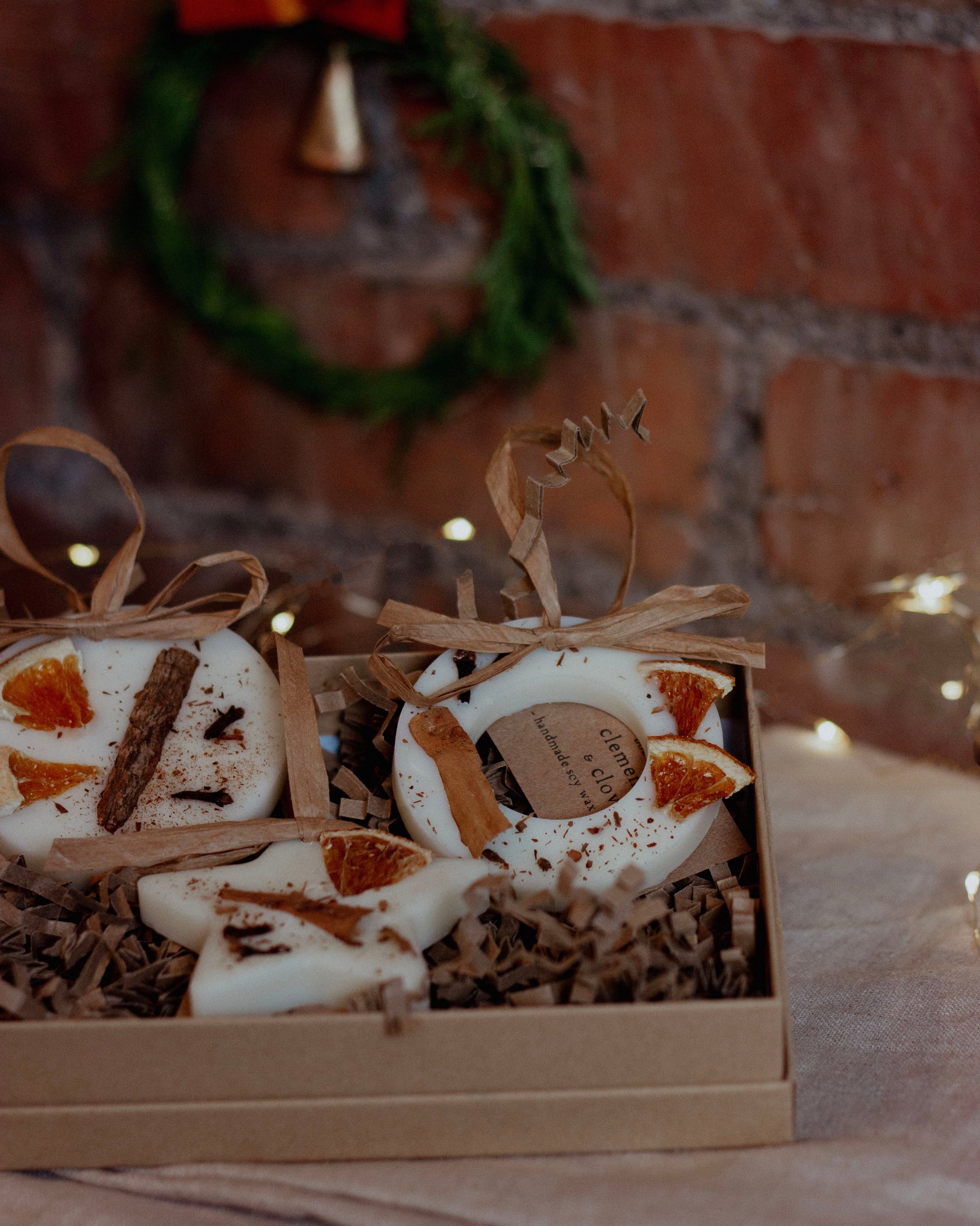Box of decorative items with a wreath in the background on a brick wall.