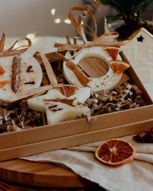 Decorative star-shaped wax melts with cinnamon sticks and orange slices on a wooden surface.